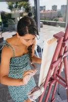 jong vrouw artiest verven met een spatel Aan de canvas foto