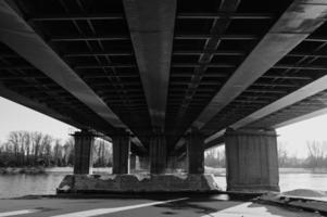 een asfalt weg onder een staal brug structuur in de stad. nacht stad tafereel met auto rijstroken. foto