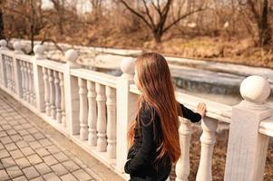 een meisje met lang haar- is wandelen in de park. mooi warm zonsondergang. een foto van een mooi jong vrouw glimlachen Bij de wind in lang gekruld brunette haar.