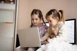 twee meisjes zussen aan het kijken Aan laptop. technologie en huis concept. foto