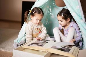 twee meisjes zussen Bij wigwam tent op zoek Bij ouders bruiloft album. foto