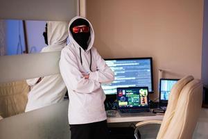 jongen hacker. internet diefstal . Mens vervelend een bivakmuts achter een laptop. foto