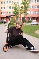 een tiener- meisje is zittend Aan een scooter met een telefoon en lachend. virtueel communicatie foto