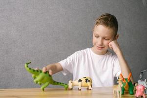 een schattig jongen zetten dier figuren Aan de tafel, een portret van een kind foto