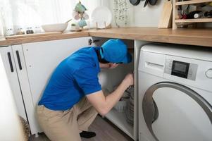 een Aziatisch jong technicus onderhoud Mens vervelend blauw uniform controle elektrisch huishoudelijke apparaten in huis foto