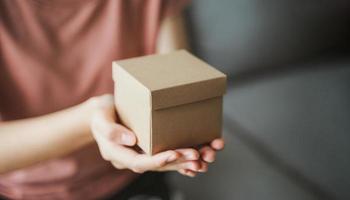 close-up van vrouw handen met een kleine geschenkdoos. kleine huidige doos in de handen van de vrouw. foto