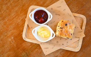 scones en jam Aan houten bord, geserveerd scones en room voor toetje en thee - vers eigengemaakt boter scones foto