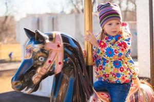 weinig meisje Aan een carrousel foto