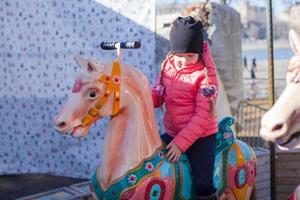 weinig meisje Aan een carrousel foto