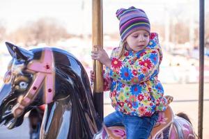 weinig meisje Aan een carrousel foto