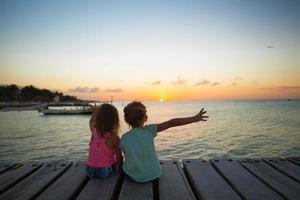 weinig meisjes Aan de pier over- de zonsondergang foto