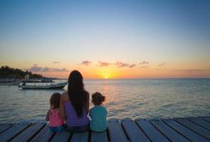 mam en dochters Aan de pier over- de zonsondergang foto