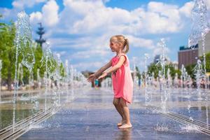 weinig meisje spelen Aan een water fontein foto