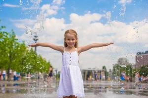 weinig meisje spelen Aan een water fontein foto