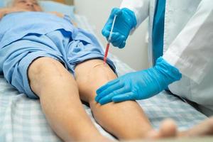Aziatische arts injecteert hyaluronzuur bloedplaatjes rijk plasma in de knie van senior vrouw om te lopen zonder pijn. foto
