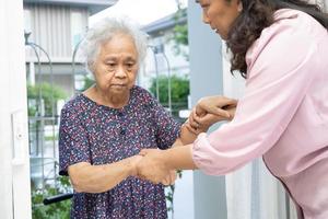 verzorger helpen en ondersteuning Aziatisch senior vrouw terwijl wandelen, stepping omhoog naar de deur van de huis. foto