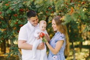 een Europese familie in de park Aan een zomer dag. mama, vader en weinig zoon zijn glimlachen in hun armen foto