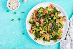 roeren bakken garnaal met broccoli dichtbij omhoog Aan een bord. garnalen en broccoli. top visie, overhead foto