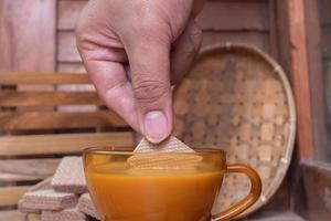 selectief focus Aan handen dompelen chocola wafel biscuits in een glas van warm cappuccino, zacht focus foto