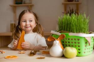 schattig weinig meisje eet natuurlijk pastille Bij huis in een houten keuken. voedsel voor kinderen van natuurlijk producten foto