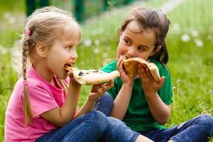 twee meisjes zittend en aan het eten pizza foto