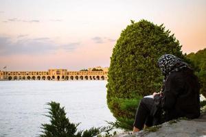 isfahan, ik rende - mei 2022, moslim leerling zitten met boek studie buiten door siose pol of brug van 33 bogen, een van de oudste bruggen van esfahan en het langst brug Aan zayandeh rivier- foto