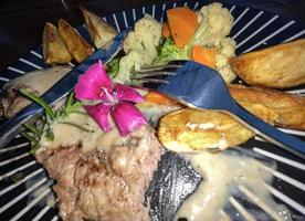 sappig rundvlees steak met salade en aardappel wiggen langs met peper maïs saus foto