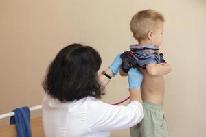 de dokter toepassingen een stethoscoop Aan de jongens terug naar controleren zijn Gezondheid. foto