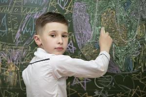 de schooljongen Bij de schoolbord trekt met krijt. midden- school- leeftijd. de jongen is in de klas. foto