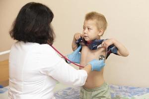 de dokter toepassingen een stethoscoop Aan de jongens maag naar controleren zijn Gezondheid. foto