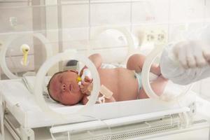 een pasgeboren baby leugens in dozen in de ziekenhuis. een kind in een broedmachine. neonataal en prematuur intensief zorg eenheid foto