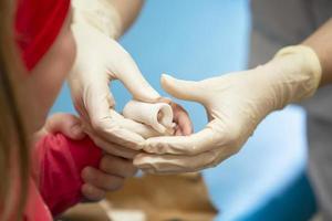 de handen van de dokter verband de zeer vinger met een verband van de kind. letsel en wond Aan de vinger in kinderen foto