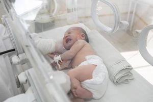 een pasgeboren baby leugens in dozen in de ziekenhuis. een kind in een broedmachine. neonataal en prematuur intensief zorg eenheid foto