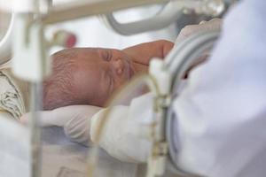 een pasgeboren baby leugens in dozen in de ziekenhuis. een kind in een broedmachine. neonataal en prematuur intensief zorg eenheid foto