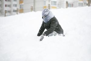 een jongen hartelijk gekleed Toneelstukken in de sneeuw Aan een winter dag. foto