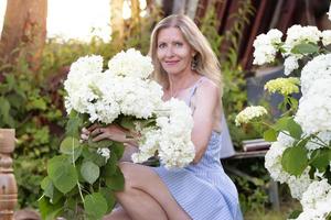 mooi ouderen vrouw met een boeket van bloemen. glimlachen vrouw in haar tuin. foto