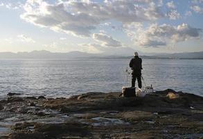 spectaculair landschap Bij de kust van enoshima, Japan, met een eenzaam visser staand Bij de rand naar de water foto