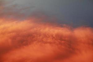 dramatisch zonsonderganglandschap met gezwollen wolken verlicht door oranje ondergaande zon en blauwe lucht. foto