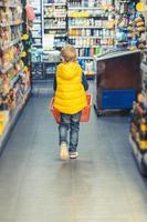 weinig jongen boodschappen doen in supermarkt. foto