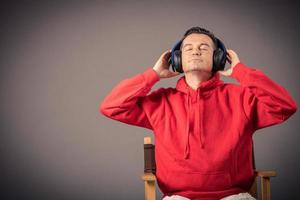 Mens vervelend hoofdtelefoons terwijl luisteren muziek- tegen de muur. foto