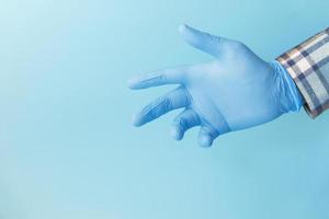 doktershand met een handschoen op blauwe achtergrond foto