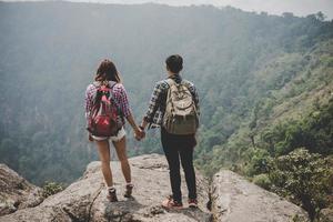 wandelaarpaar met rugzakken die zich bovenop een berg bevinden en genieten van uitzicht op de natuur
