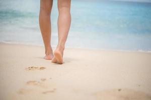 close-up van de benen van de vrouw die op het strand lopen foto