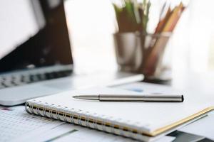 laptop met Kladblok en pan op glazen bureau in kantoor foto