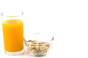 pistachenoten in een glazen plaat en een glas jus d'orange op wit wordt geïsoleerd foto