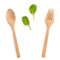 groene bladeren met houten lepel en vork op wit foto