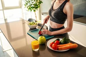 atletisch meisje met Sportschool kleren eet een salade in de keuken foto