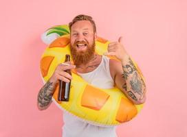 gelukkig Mens is klaar naar zwemmen met een donut redder in nood met bier en sigaret in hand- foto