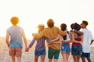 groep van gelukkig vrienden hebben pret Bij oceaan strand foto