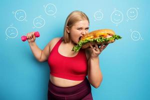 dik meisje doet Sportschool en willen naar eten een Sandwich. concept van besluiteloosheid en twijfel foto